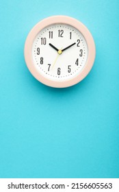 Pink clock on blue background. Top view. Vertical photo