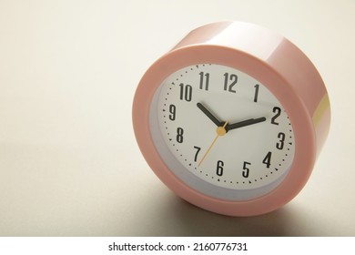 Pink clock on grey background. Top view. Space for text
