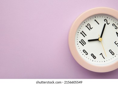 Pink clock on purple background. Top view. Macro