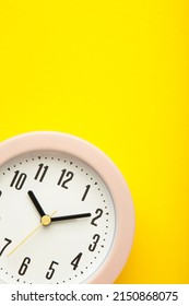 Pink clock on yellow background. Top view. Vertical photo