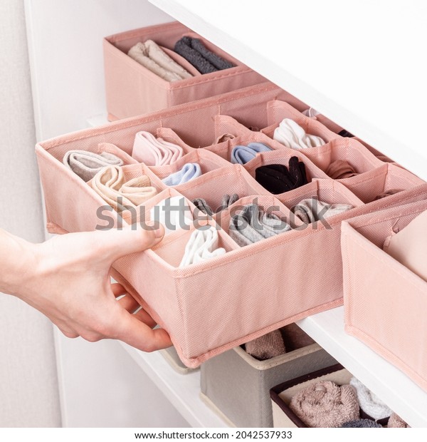 Pink closet organizers\
drawer divider. Order in closet. Neatly folded socks. Man sorts\
laundry. Square
