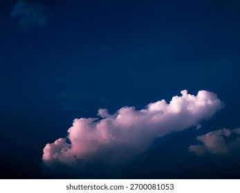 Pink clouds floating in a deep blue sky at twilight, showing the peaceful beauty of nature and a calm evening mood
