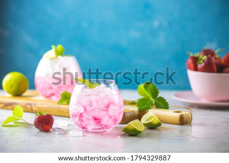 Pink cocktail with lime, crushed ice, strawberries and mint on the light background, selective focus image, copy spice for you text, summer vacation and party concept.