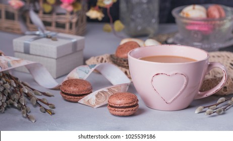 Pink Coffee Mug With Sweet Pastel French Macaroons, Gift Box And Pussy Willow On Light Table From Above. Breakfast On Mothers Day Or Women's Day. Tender Spring Background.