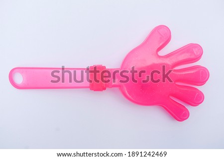 Pink color hand clapper toy Palm shaped clapper children toys.Also used during kite festival uttarayan to make noice when kite is cut. Plastic object isolated on white background. prop used for partyi