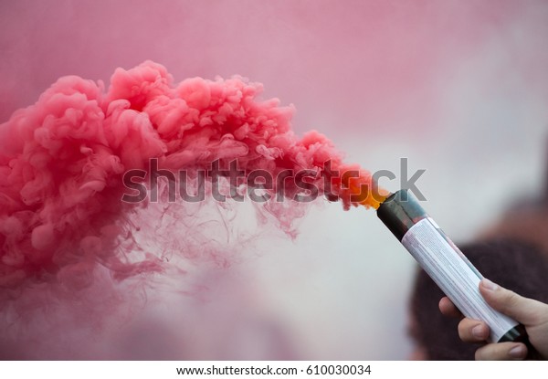 pink color smoke bomb in\
human hand