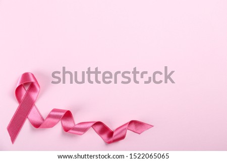 The pink colored ribbon - international symbol of breast cancer awareness and moral support for women. Paper textured background, copy space, close up, top view fat lay.