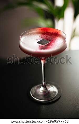 pink colored strawberry cocktail on bar table, with modern garnish