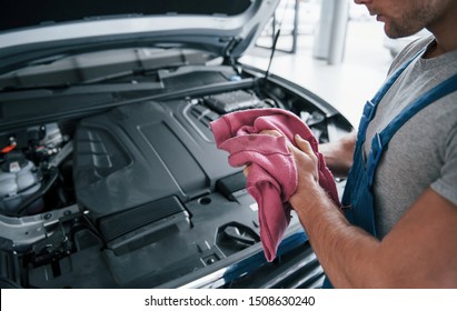 Pink colored towel. Man in blue uniform works with broken car. Making repairings. - Shutterstock ID 1508630240