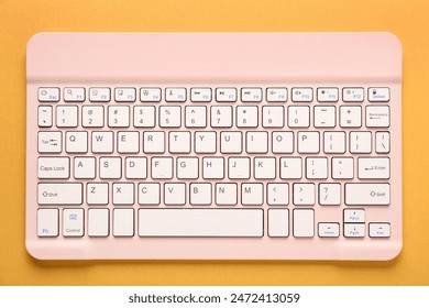 Pink computer keyboard on orange background. Top view