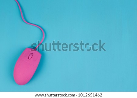 Pink computer mouse on blue background, copy space