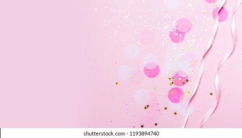 Pink confetti and stars and sparkles on pink background. Top view, flat lay. Copyspace for text. Bright and festive holiday background. For Christmas, New year, Mother's day.