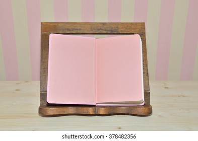 Pink Cook Book On Wooden Book Holder With Pink-yellow Kitchen Wall