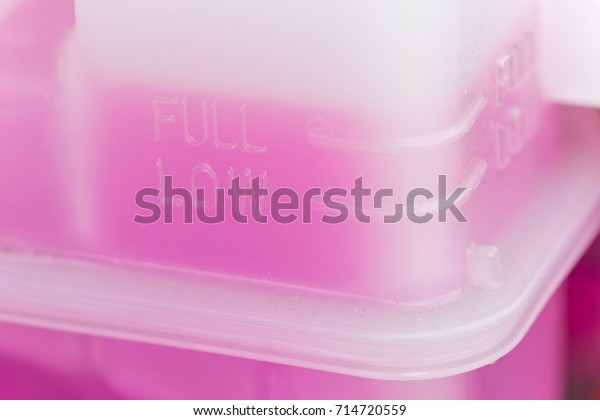 Pink cooling\
fluid in a plastic container - engine of a hybrid car powered both\
by electric battery and\
gas
