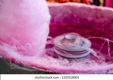 Pink cotton sweet in candy machine.Fluffy sugar product on festival.Sweet cotton dessert close up