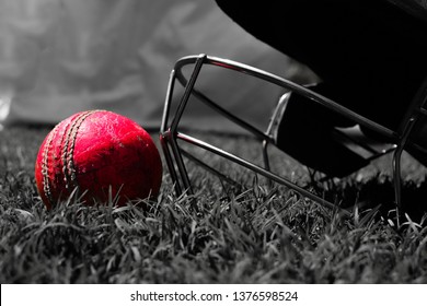 Pink cricket ball with halmet on green grass. Black and white 