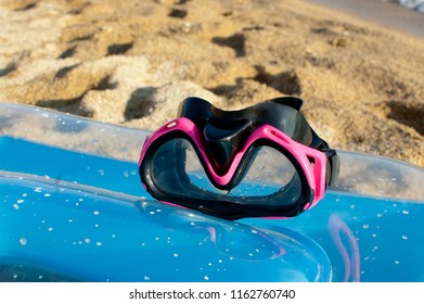 pink diving mask for girls on blue sea ​​mattress on sunny day at the beach with sand as background, close up - Shutterstock ID 1162760740