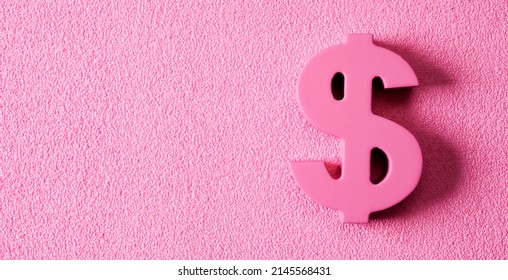 a pink dollar sign, depicting concepts such as pink money or pink capitalism, on a textured pink background with some blank space on the left - Shutterstock ID 2145568431