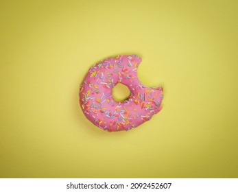 Pink Donut With A Bite Mark On A Yellow Background