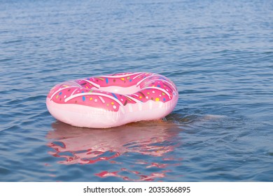 Pink Donut Rubber Ring Floats In The Crystal Blue Sea In Summer