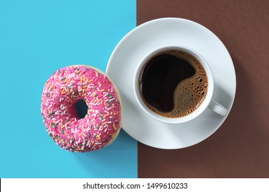 Pink donut with sprinkles and cup of coffee on two-tone background, top view - Powered by Shutterstock