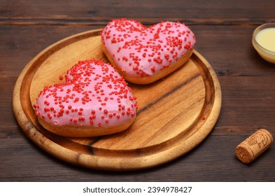 donuts rosas en forma de corazón sobre un tablero de madera cerca