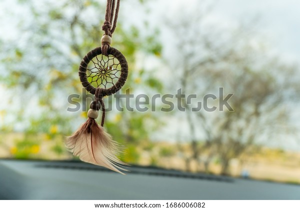 pink dream catcher hanging with a down feather and\
tree bottom inside a car