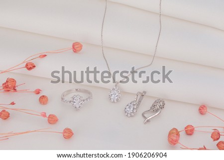 pink dried flowers and jewelry set on white folded fabric