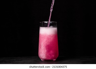 Pink Drink Is Poured Into A Glass On A Black Background. Carbonated Sweetwater. Delicious Drink