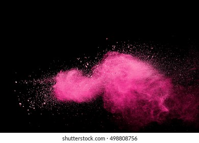 Pink dust debris isolated on black background, motion powder spray burst in dark texture