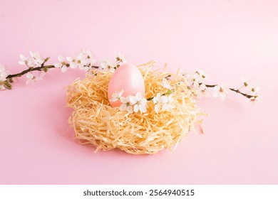 Pink easter egg in a nest of straw and white flowering tree branches on the pink background. Close-up. - Powered by Shutterstock