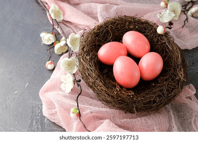 Pink Easter eggs in a bird's nest with white flowers on a pink fabric background