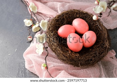 Pink Easter eggs in a bird's nest with white flowers on a pink fabric background