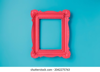 A pink empty frame isolated on the vibrant blue background. Decorative detail, retro inspired backdrop. Creative pop art antique frame concept. Juxtapose of and vintage and contemporary style.