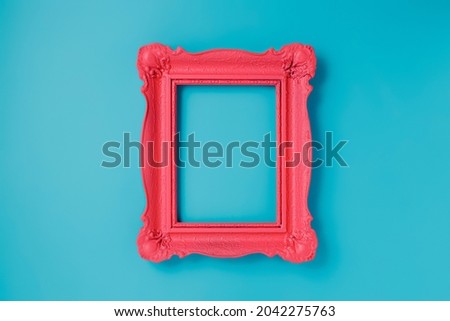 A pink empty frame isolated on the vibrant blue background. Decorative detail, retro inspired backdrop. Creative pop art antique frame concept. Juxtapose of and vintage and contemporary style.
