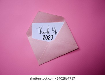 The Pink envelope with a white card with the word thank you 2023. Bye 2023. Bye December 2023. welcome 2024.