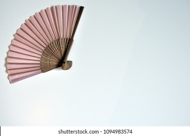 Pink fan on the up left corner on white background, flat lay, copy space, minimalist style