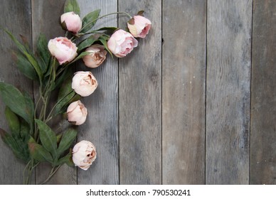 Pink faux flowers on wooden background 