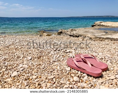 Pink flip flops on the pebble beach of Mandre, Pag island, Croatia