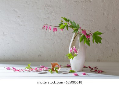 pink flowers in broken vase on old white background