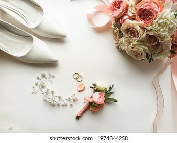 Pink flowers, pearl jewelry and two gold wedding rings on a white background. Wedding concept. Isolated