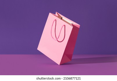 Pink flying paper shopping bag on purple background. Shopping sale delivery concept - Shutterstock ID 2106877121