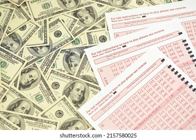Pink gambling sheets with numbers for marking on big amount of hundred dollar bills. Lottery playing concept or gambling addiction. Close up photo