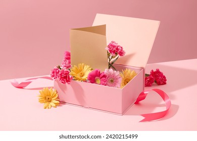 A pink gift box fill with beautiful gerbera and carnation and paper card decorated on a sweet pink background. Copy space for international women's day. Front view - Powered by Shutterstock