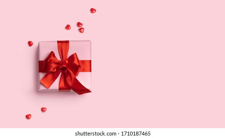 Pink gift box with red bow on pink background with red hearts. Holiday web banner. Top view. - Powered by Shutterstock