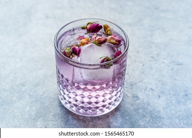 Pink Gin Tonic Cocktail with Dried Rose Buds, Purple Lavender and Ice in Glass Cup