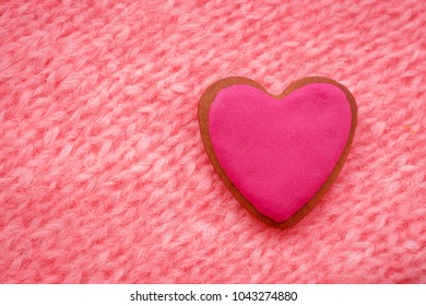 pink gingerbread in shape of heart on pink knitted background