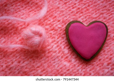pink gingerbread in shape of heart on a background of pink knitted fabric