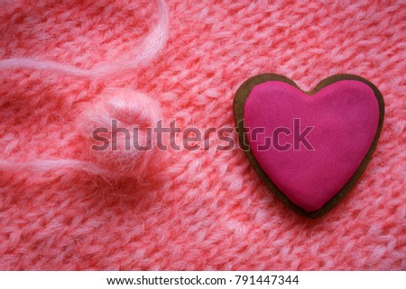 pink gingerbread in shape of heart on a background of pink knitted fabric