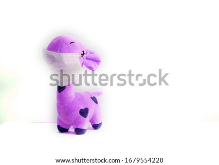 
pink giraffe toy in a medical mask on a white background